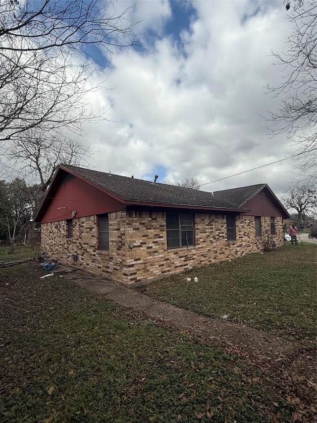 view of property exterior with brick siding and a lawn