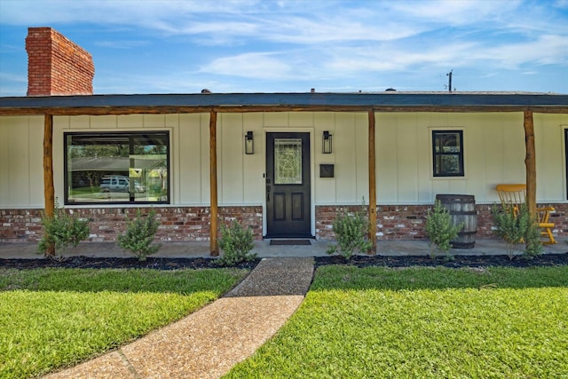 property entrance with board and batten siding, brick siding, and a yard