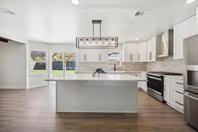 kitchen with stainless steel appliances, a center island, visible vents, and wall chimney range hood