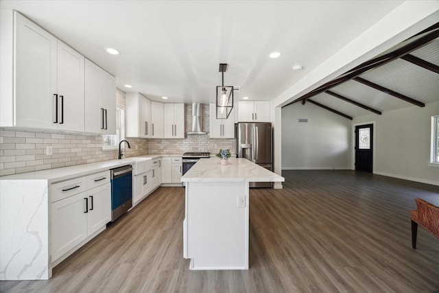 kitchen with light stone counters, open floor plan, appliances with stainless steel finishes, wall chimney range hood, and decorative backsplash