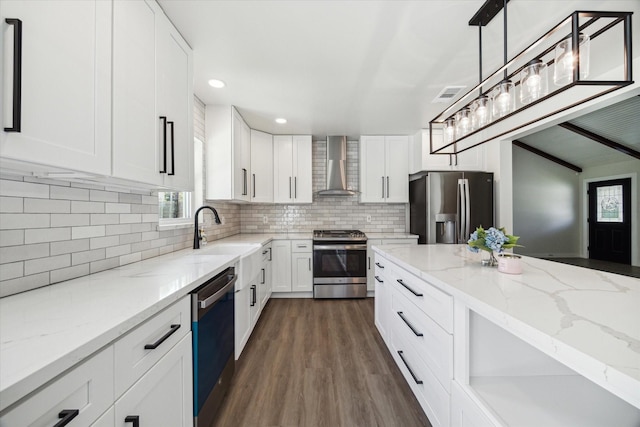 kitchen featuring stainless steel appliances, visible vents, backsplash, a sink, and wall chimney exhaust hood