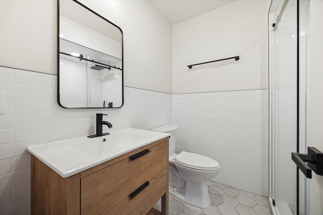 full bath featuring tile walls, toilet, vanity, a shower stall, and tile patterned floors