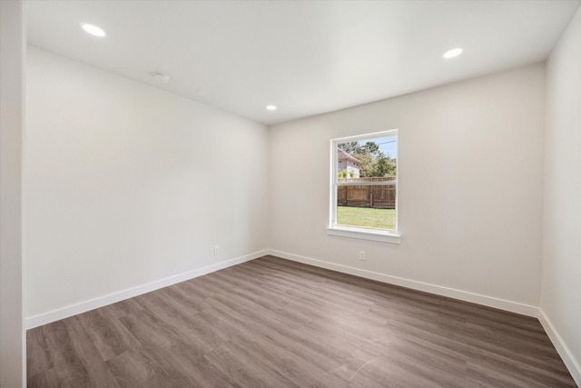 empty room with dark wood-type flooring, recessed lighting, and baseboards