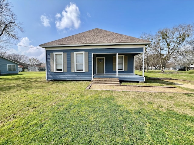 back of property featuring a shingled roof, covered porch, and a lawn