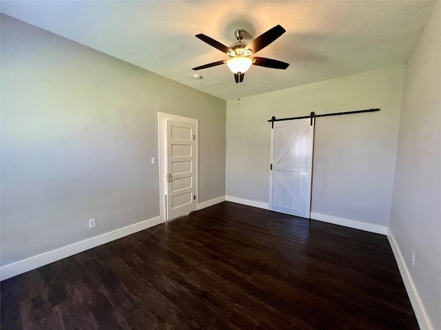 unfurnished bedroom featuring wood finished floors, a textured ceiling, baseboards, and a barn door