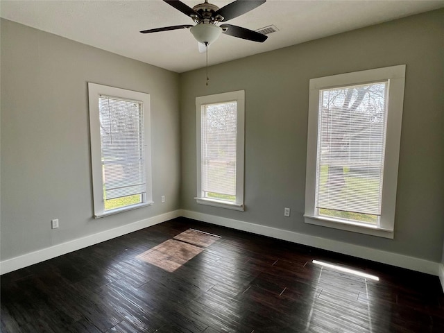 unfurnished room with baseboards, visible vents, ceiling fan, and dark wood-type flooring