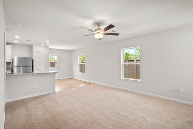 unfurnished living room with light carpet, ceiling fan, recessed lighting, and baseboards