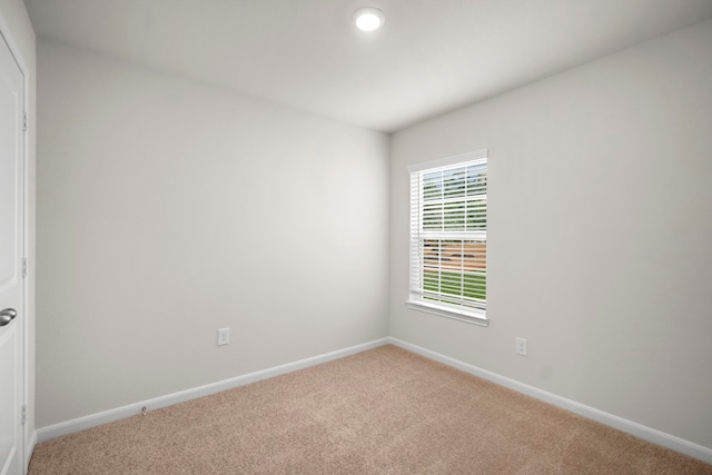 unfurnished room with baseboards and light colored carpet