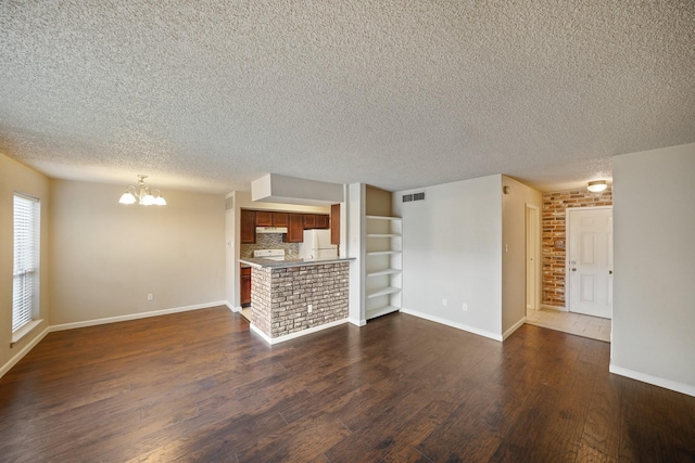 unfurnished living room with baseboards, visible vents, dark wood finished floors, a textured ceiling, and a chandelier