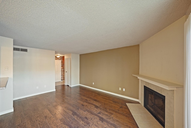 unfurnished living room featuring a textured ceiling, a fireplace, wood finished floors, visible vents, and baseboards