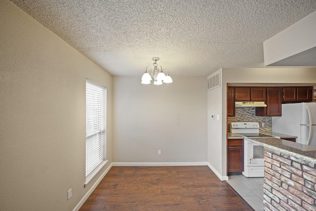 kitchen featuring under cabinet range hood, white appliances, visible vents, light wood-style floors, and backsplash