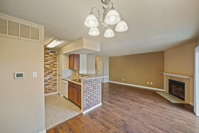 kitchen featuring visible vents, open floor plan, wood finished floors, a tile fireplace, and dishwasher