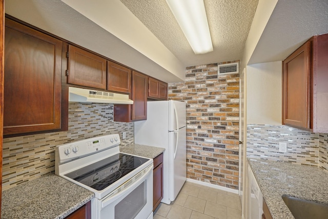 kitchen featuring white appliances, light tile patterned floors, visible vents, light stone countertops, and under cabinet range hood