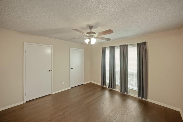 empty room featuring a textured ceiling, dark wood-type flooring, a ceiling fan, and baseboards