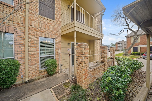 entrance to property featuring brick siding and a balcony