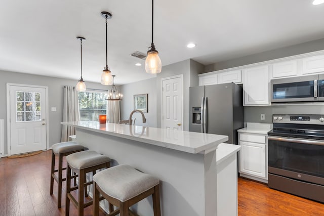 kitchen with a breakfast bar, visible vents, stainless steel appliances, and white cabinets