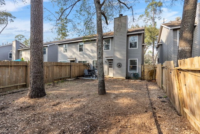 back of house featuring a chimney, a patio area, and a fenced backyard