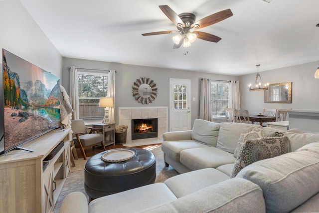 living room featuring ceiling fan with notable chandelier and a fireplace