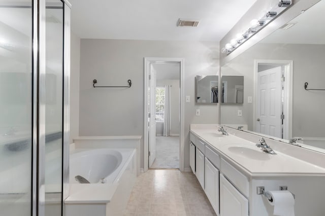 bathroom with double vanity, a sink, a bath, and a shower stall