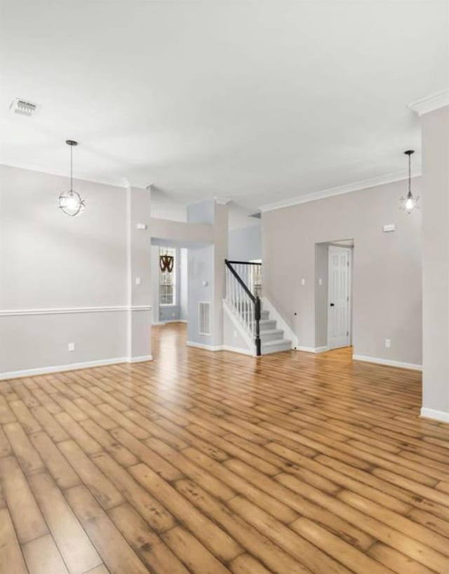 unfurnished living room with visible vents, baseboards, stairs, light wood-type flooring, and crown molding