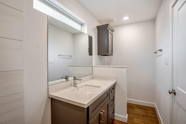 bathroom with recessed lighting, visible vents, vanity, wood finished floors, and baseboards