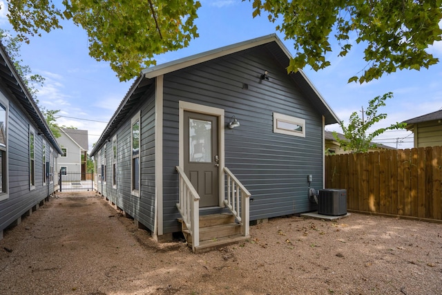 back of house featuring central AC unit, fence, and entry steps