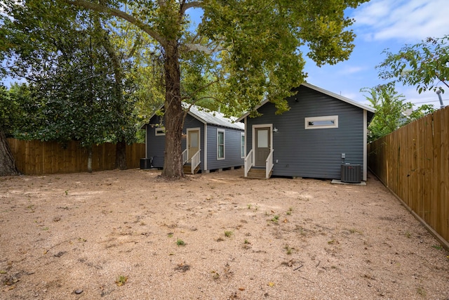 back of property with entry steps, central AC unit, an outdoor structure, and a fenced backyard