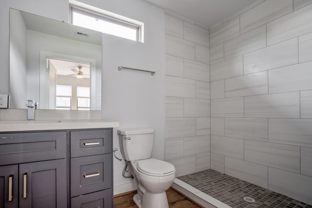 full bathroom featuring visible vents, a tile shower, vanity, and toilet