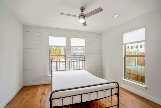 bedroom with wood walls, light wood-style flooring, and baseboards