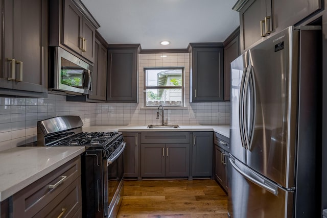 kitchen with stainless steel appliances, tasteful backsplash, a sink, and light countertops