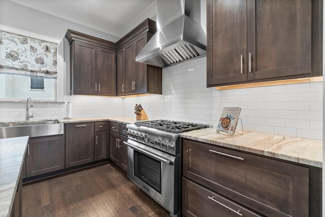 kitchen with dark brown cabinetry, dark wood-style floors, wall chimney exhaust hood, high end range, and a sink