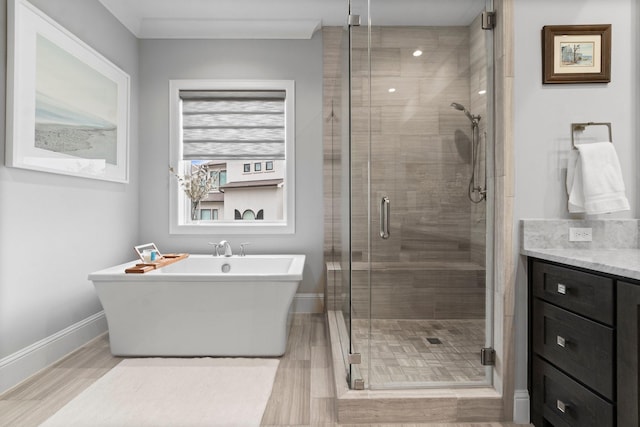 bathroom with a freestanding bath, a shower stall, baseboards, and vanity