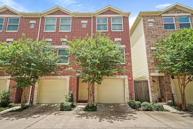 view of property featuring driveway, brick siding, and an attached garage