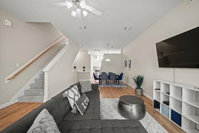 living room featuring visible vents, stairway, baseboards, and wood finished floors