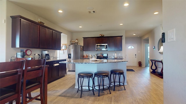kitchen with light wood finished floors, stone counters, visible vents, and appliances with stainless steel finishes