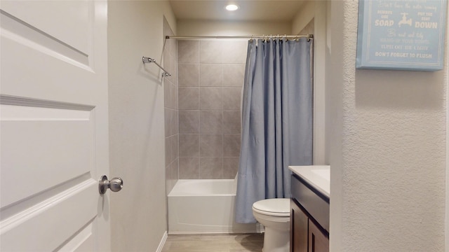 bathroom featuring a textured wall, toilet, wood finished floors, vanity, and shower / bath combo with shower curtain