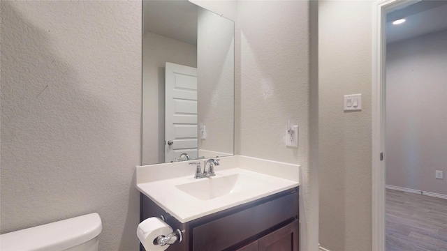 bathroom featuring a textured wall, vanity, toilet, and wood finished floors