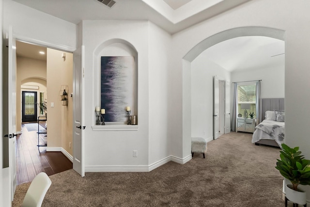 corridor featuring carpet, arched walkways, and baseboards