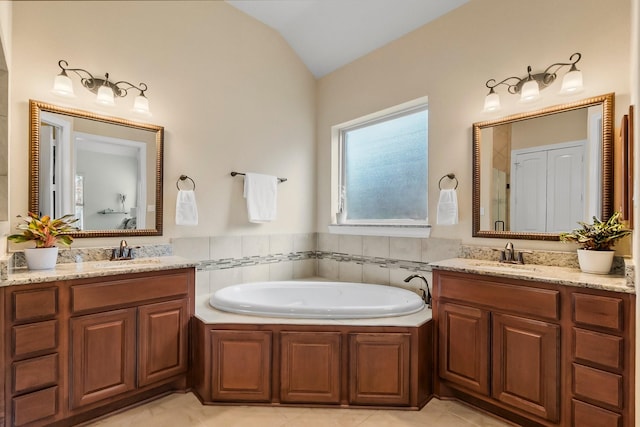 full bath featuring lofted ceiling, two vanities, a sink, and a bath