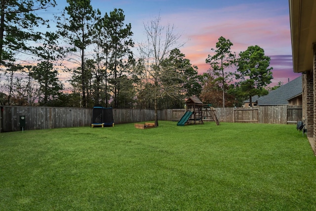 yard at dusk with a playground and a fenced backyard