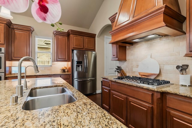 kitchen with decorative backsplash, custom range hood, light stone countertops, stainless steel appliances, and a sink