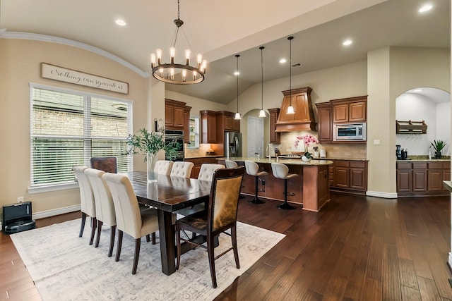 dining area featuring baseboards, arched walkways, lofted ceiling, dark wood-style floors, and a chandelier