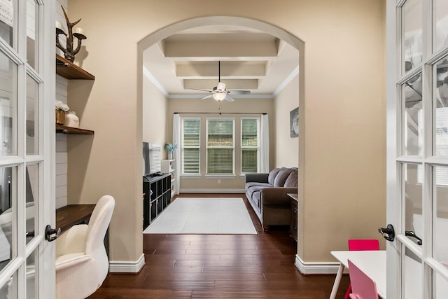 office area with arched walkways, ceiling fan, dark wood-style flooring, coffered ceiling, and baseboards