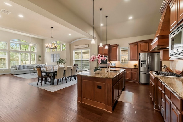 kitchen with visible vents, appliances with stainless steel finishes, dark wood-type flooring, light stone countertops, and a sink