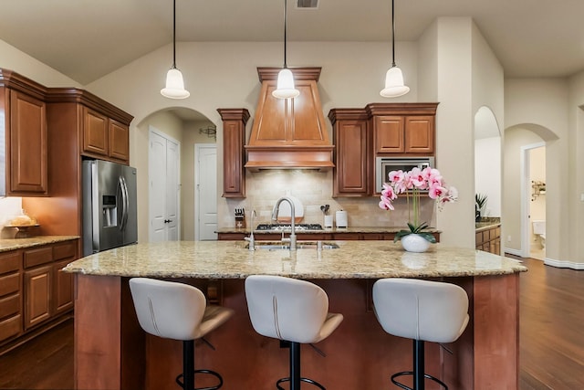 kitchen featuring appliances with stainless steel finishes, arched walkways, dark wood-style flooring, and vaulted ceiling