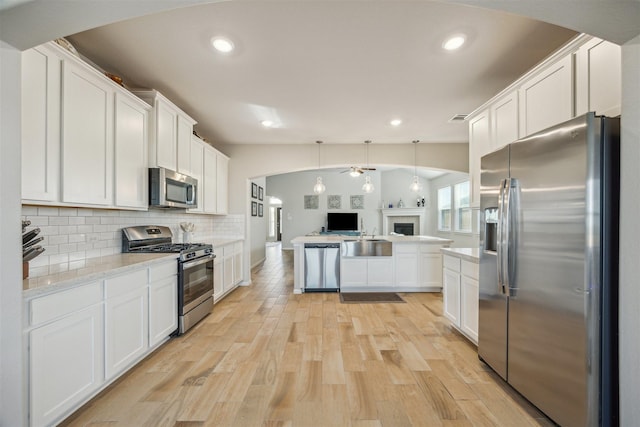 kitchen featuring white cabinets, stainless steel appliances, decorative backsplash, and open floor plan