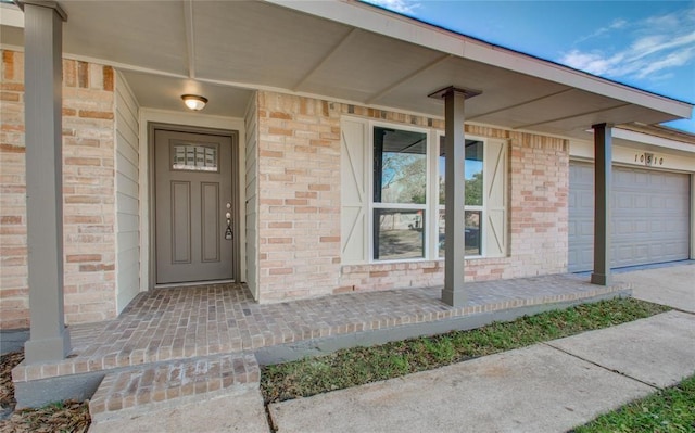 doorway to property with brick siding, a porch, and an attached garage