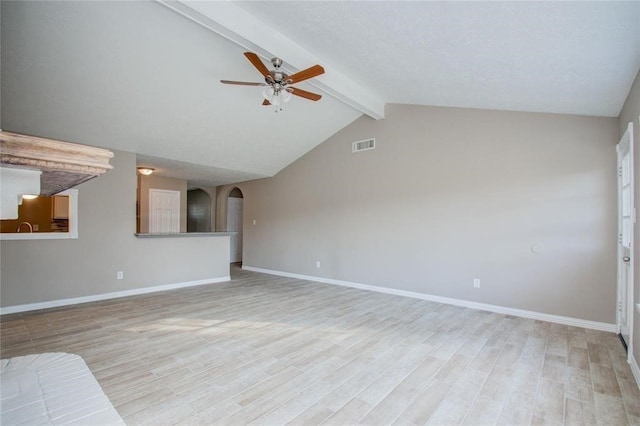 unfurnished living room featuring light wood-type flooring, lofted ceiling with beams, visible vents, and arched walkways