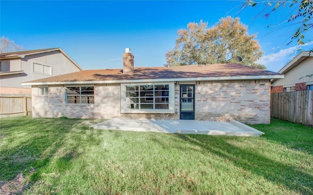 back of property with a chimney, a fenced backyard, and a lawn