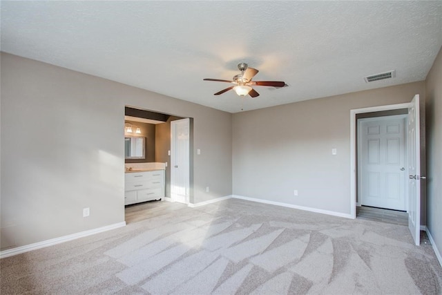 unfurnished bedroom with light colored carpet, visible vents, a textured ceiling, and baseboards